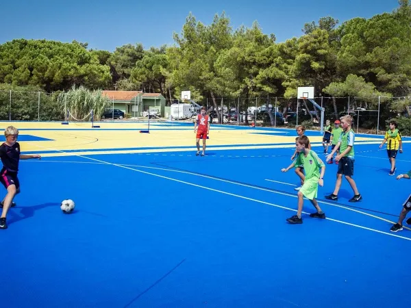 Playing soccer on multi-sport field at Roan campsite Zaton Holiday resort.