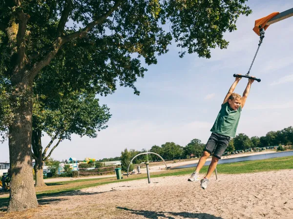 Child swinging on play rope in playground at Roan camping the Schatberg.