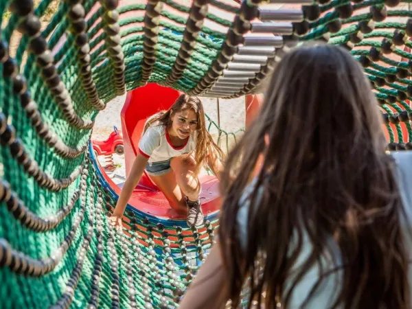 Climbing the climbing net in the indoor play forest at Roan camping De Schatberg.