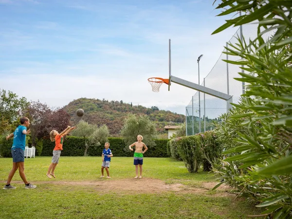 Kids play basketball at Roan camping La Rocca Manerba.