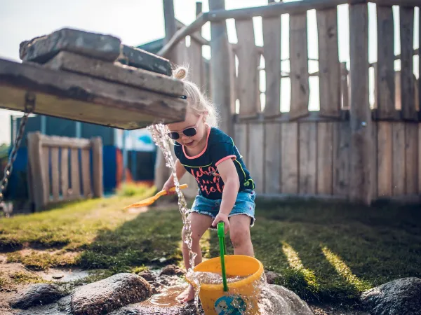 Child playing with water in the waterfall valley at Roan camping Ackersate.