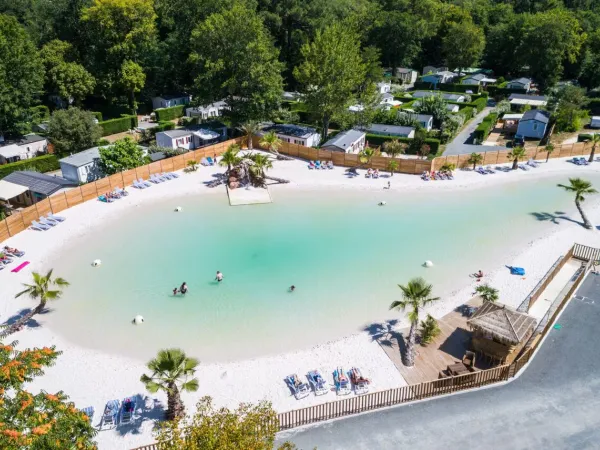 Overview of lagoon pool with sandy beach at Roan camping La Clairière