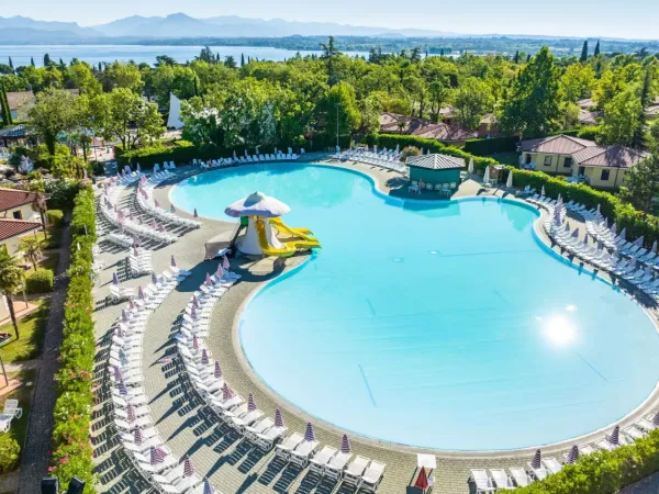 Swimming pool with slides and sunbeds at Roan camping Bella Italia.