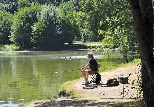 Man fishing in the fishing pond at Roan campsite Domaine de la Brèche.