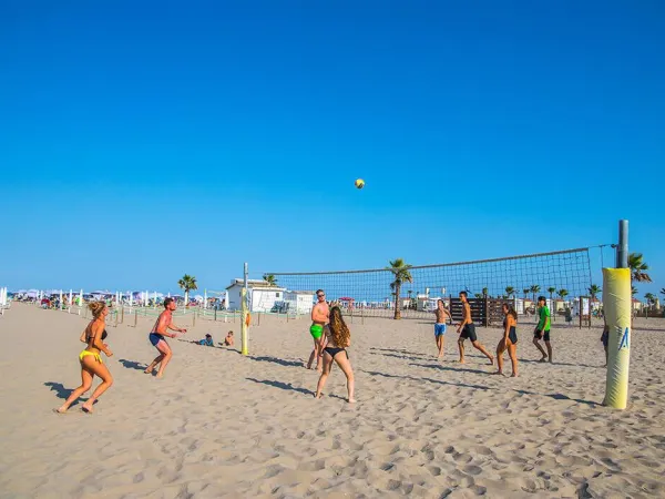 Vacationers play beach volleyball at Roan camping Sole Family Camping Village.