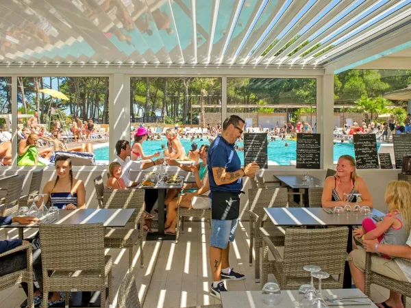 A full terrace by the pool at Roan camping Le Castellas.