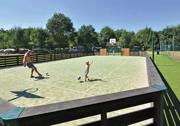 Father and son play football on the football pitch at Roan campsite Domaine de La Brèche.