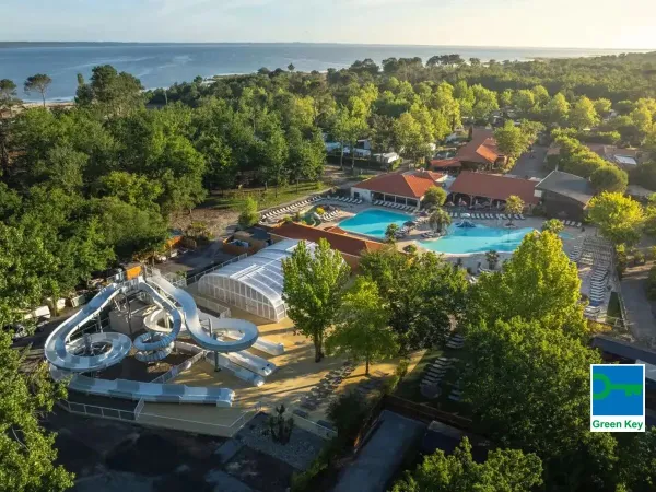 Overview of pool with slide and the sea in the distance at Roan camping Mayotte Vacances.