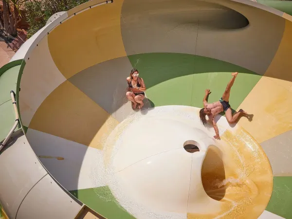 Two people have fun on the tornado slide at Roan campsite Le Petit Mousse.