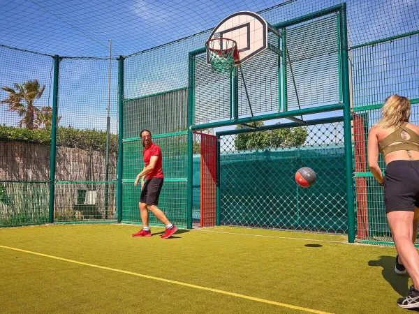 Playing basketball on the multi-purpose sports court at Roan camping Le Petit Mousse.