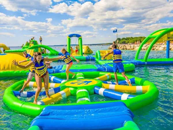 Children play on air cushions in the lake at Roan camping Le Lac des Vieilles Forges.