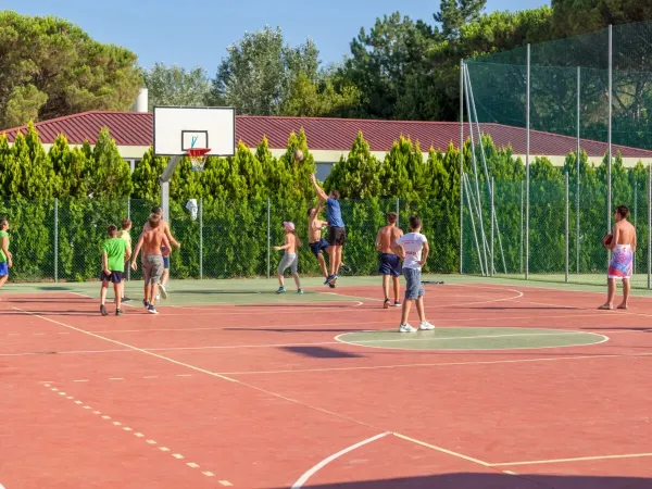 Children play a game of basketball on the multi-sports court at Roan campsite Marina Julia Camping Village.