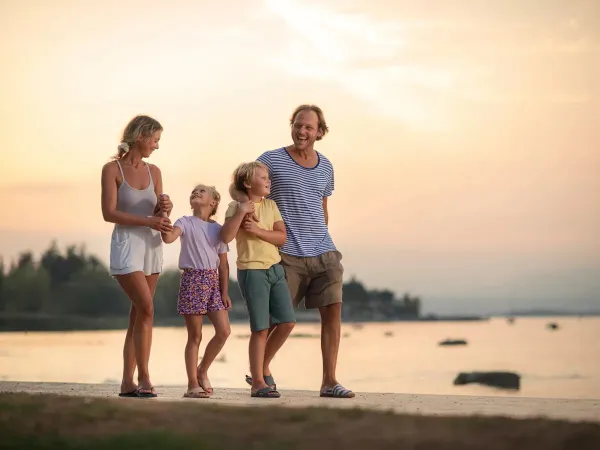Smiling family walking on the beach at sunset.