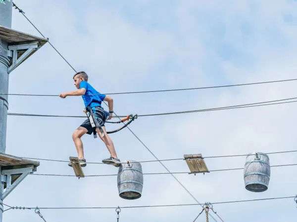 Little boy climbs the climbing course at Roan campsite Le Lac des Vieilles Forges.