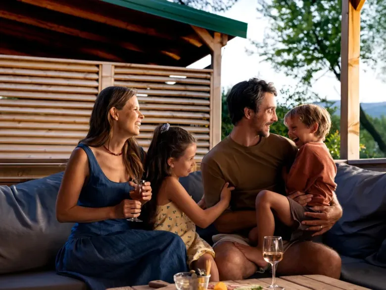 Father and children enjoying themselves on the lounge sofa of the mobile home at Roan campsite Le Petit Mousse.