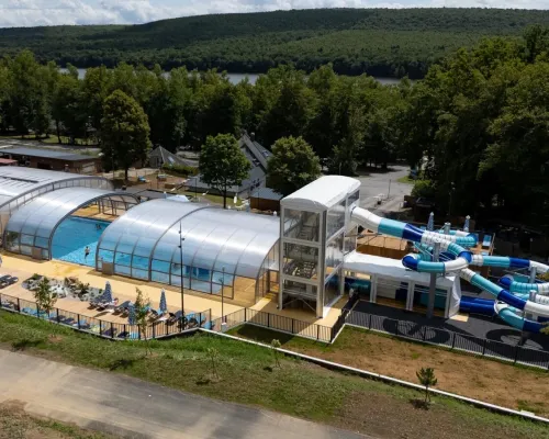 Overview swimming pool with slides and sunbeds at Roan camping Le Lac des Vieilles Forges.