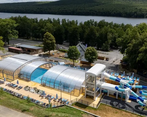 Overview swimming pool with slides and sunbeds at Roan camping Le Lac des Vieilles Forges.